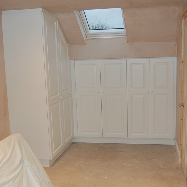white spray painted wardrobes to attic bedroom with doors to hide storage under the eaves