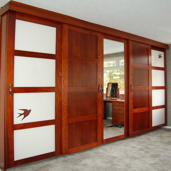 bedroom with stained oak sliding wardrobe doors with painted glass panels with bird detail and mirrored centre door