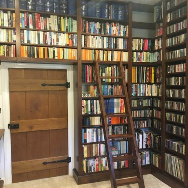 bespoke library with floor to ceiling stained pine shelving for books, CD/DVD, vinyl records and a bespoke moveable ladder