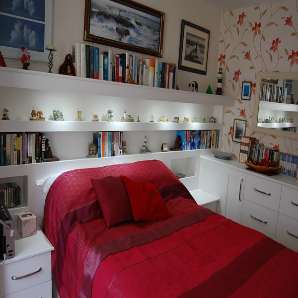 modern style bedroom with shelving and lighting incorporated in headboard