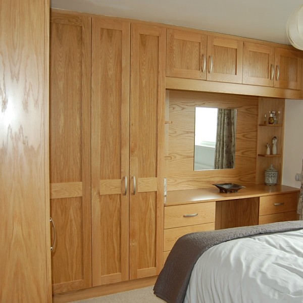 oak bedroom with shaker style wardrobe doors and dressing table with storage above